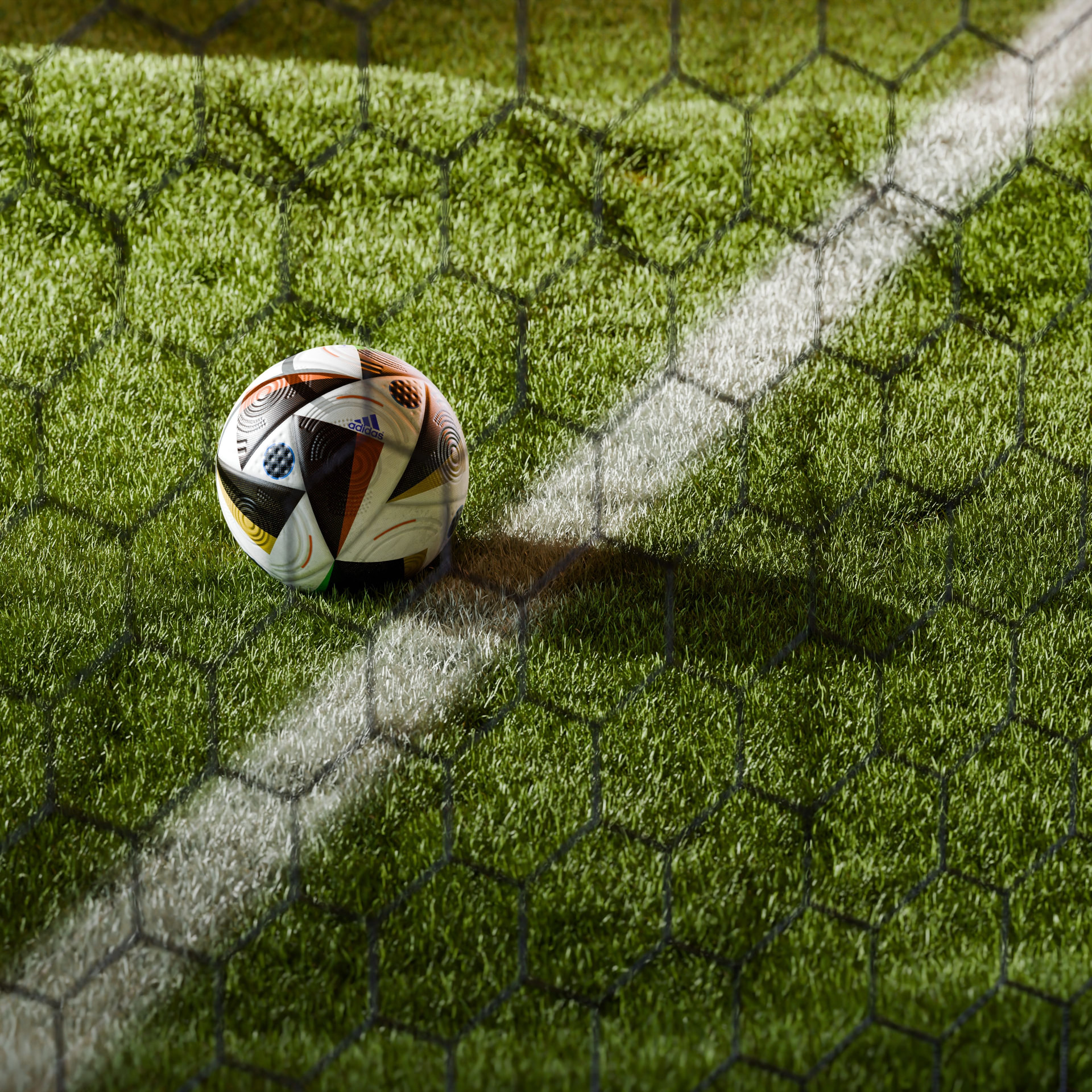 Football resting on the pitch behind a goal net